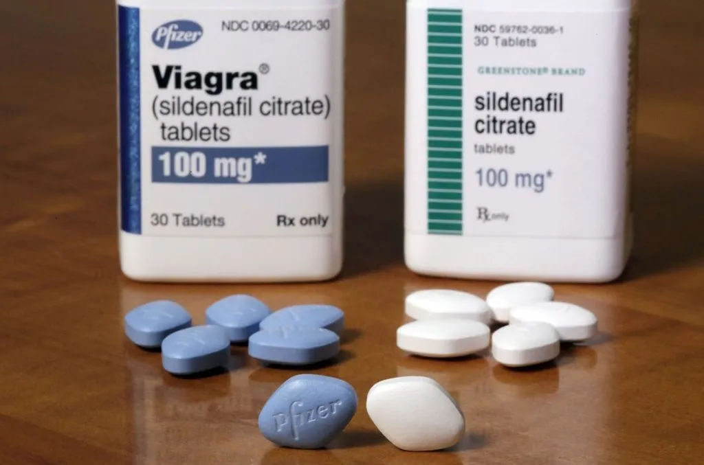 Sildenafil vs Viagra side-by-side comparison showing branded Pfizer Viagra blue diamond tablet at £20–£35 versus MHRA-licensed generic sildenafil at £5–£12 per four tablets — same active ingredient, same dose, same effect