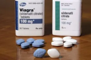 Sildenafil vs Viagra side-by-side comparison showing branded Pfizer Viagra blue diamond tablet at £20–£35 versus MHRA-licensed generic sildenafil at £5–£12 per four tablets — same active ingredient, same dose, same effect