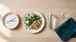 Clock, light meal and glass of water arranged to show correct sildenafil timing and food guidance in the UK